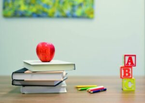 Schreibtisch mit Büchern, Stiften und Apfel
